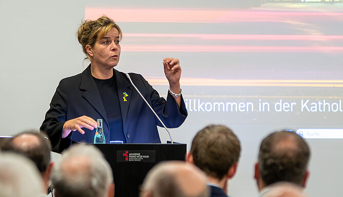 Ministerin Mona Neubaur steht an einem Rednerpult und gestikuliert, während sie spricht.