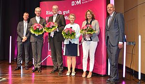 Antonius Hamers, Michael Focke, Claudia Dues und Mechthild König und Heinz-Josef Kessmann stehen auf dem Podium. Hinter ihnen ein Banner mit der Aufschrift "DKM".    