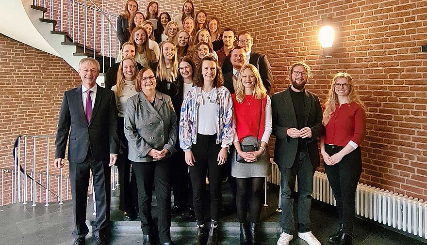 Mehrere Personen stehen zu einem Gruppenbild auf einer Treppe.