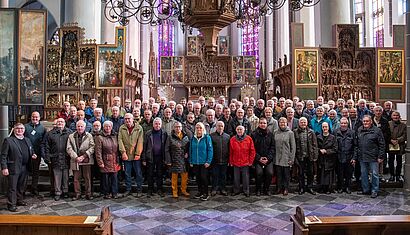 Eine große Menschengruppe steht in einer Kirche.