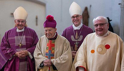 Vier Priester, davon zwei Bischöfe, stehen nebeneinander in einem Raum.