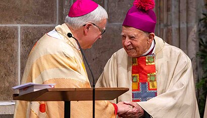 Ein Bischof reicht einem Ehrendomkapitular die Hand.