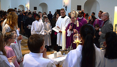 Weihbischof Geerlings und die Gläubigen stehen um eine Kerze herum, die am Ewigen Licht entzündet worden ist.