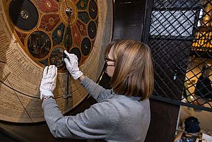 Diplom-Restauratorin Marita Schlüter setzt eine Monatsscheibe in die Astronomischen Uhr ein. 