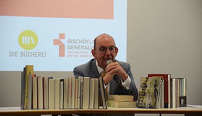 Literaturkritiker Denis Scheck hinter einem Stapel Bücher