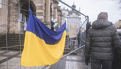 Eine ukrainische Flagge hängt an einem Zaun an einer Kirche.
