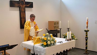 Ein Priester steht an einem gedeckten Altar.