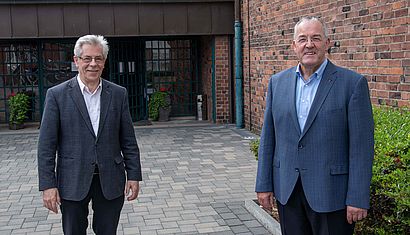 Pfarrer Werth und Pfarrer Bösing stehen mit Abstand zueinander vor der St. Martinus Kirche in Moers.