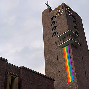 Ein Kirchturm mit Regenbogenflagge
