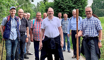 Mehrere Männer in Wanderkluft stehen auf einem Weg.