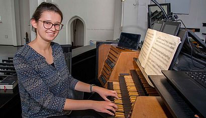 Eine junge Frau sitzt an einer Kirchenorgel.