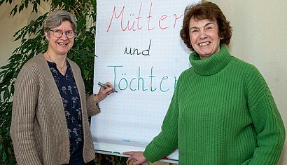 Zwei Frauen stehen vor einem Flipchart.