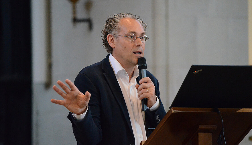 Frank Böttcher steht an einem Rednerpult im St.-Paulus Dom in Münster. Er hält einen Vortrag über Handlungsmöglichkeiten angesichts des laufenden Klimawandels.