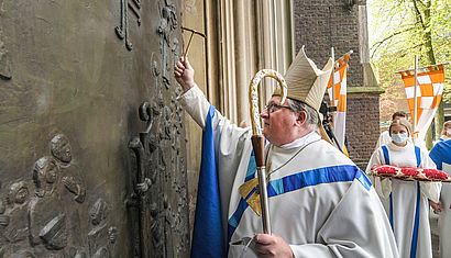 Abt Albet Dölken schlägt mit einem Hammer gegen das Pilgerportal der Marienbasilika.