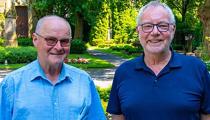Zwei Männer stehen auf einem Friedhof
