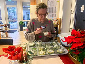Eine Frau sitzt auf einem Stuhl an einem Tisch und bereitet Desserts zu.