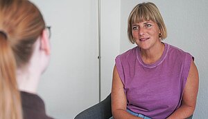 Zwei Frauen sitzen sich gegenüber und sprechen miteinander.