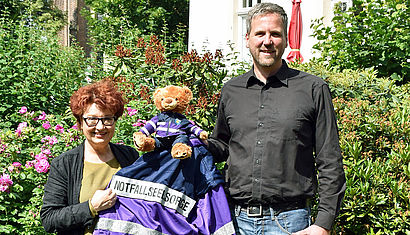 Alexandra Hippchen und Andreas Naumann-Hinz halten gemeinsam eine Jacke der Notfallseelsorge in den Händen.