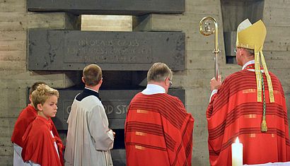 Bischof Overbeck steht auf der rechten Seite mit dem Rücken zum Betrachter und betrachtet die Gedenkstätte für Nikolaus Groß.