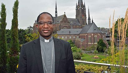 Erzbischof Laurent Lompo steht bei einem Besuch in Deutschland vor der Marienbasilika in Kevelaer.