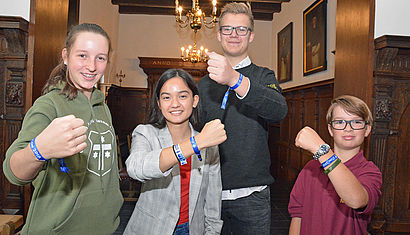 Vier Schüler stehen nebeneinander und zeigen die blauen Armbänder der Romwallfahrt an ihren Handgelenken. Die Schüler sind (von links) Emma, Marie-Sah, Simon und Niclas.