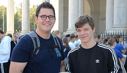 Zwei junge Männer stehen nebeneinander im Freien.