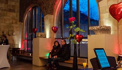 Im Paradies der Jakobikirche steht eine rote Rose, im Hintergrund ist ein Paar zu sehen.