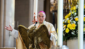 Bischof Felix Genn steht im St. Paulusdom am Ambo und spricht in ein Mikrofon. Die rechte Hand hat er gestikulierend ausgestreckt.