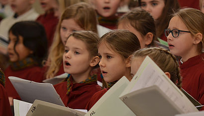 Die Mädchen des Mädchenchores am Dom halten Notenhefte in den Händen und singen.