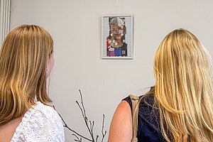 Zwei junge Frauen schauen sich ein Puzzle an, das an der Wand hängt. 
