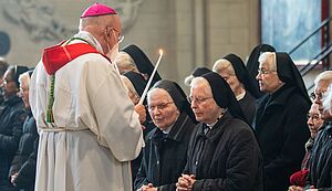 Bischof Felix Genn segnet die Ordensjubilarinnen mit zwei in Form des traditionellen Blasiussegens mit übereinander gekreuzt gehaltenen Kerzen.
