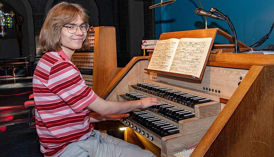 Ein junger Mann sitzt an einer Kirchenorgel.