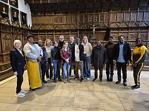 In einem Raum mit dunkelbrauner Vertäfelung (Friedenssaal) stehen mehrere Personen nebeneinander mit verschiedener Ethnizität. Unter den Personen befinden sich sowohl Jugendliche, als auch Erwachsene. In einem Raum mit dunkelbrauner Vertäfelung (Friedenssaal) stehen mehrere Personen nebeneinander mit verschiedener Ethnizität. Unter den Personen befinden sich sowohl Jugendliche, als auch Erwachsene.