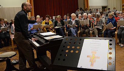 Ein Chorleiter steht vor einem großen Chor.