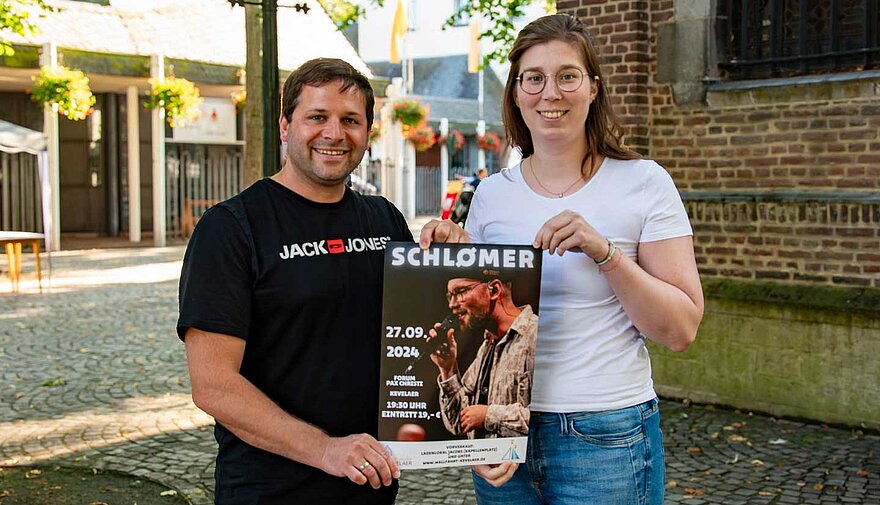 Ein Mann und eine Frau halten ein Plakat.