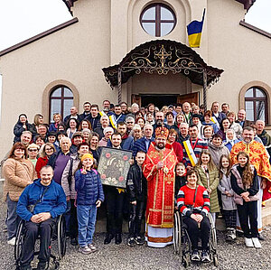 Eine Menschenmenge steht aufgereiht vor einer Kirche, an der die Flagge der Ukraine weht. Eine Menschenmenge steht aufgereiht vor einer Kirche, an der die Flagge der Ukraine weht.
