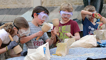 Kommunionkinder bearbeiten einen Baumberger Sandstein.