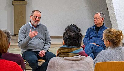 Zwei Männer sind vor Publikum im Gespräch miteinander.