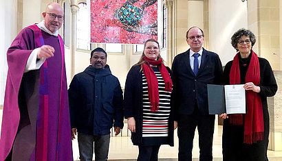 Zwei Frauen und drei Männer stehen in einer Kirche.