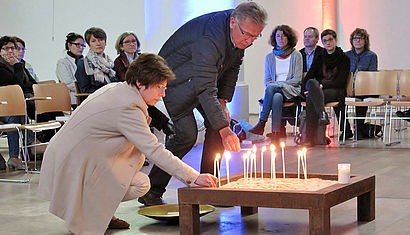 Menschen entzünden Kerzen in einer Kirche.