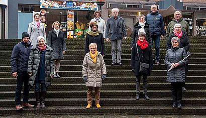 Mehrere Menschen stehen verteilt auf einer großen Treppe im Freien.