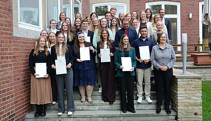 30 junge Menschen halten ihre Zertifikate fürs Foto vor sich. 