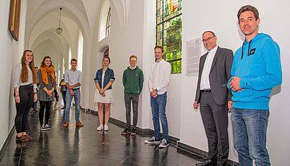 Sechs Schülerinnen und Schüler, Weihbischof Rolf Lohmann und Lehrer Dr. Mathias Henkel stehen im Kreuzgang der Gaesdonck.