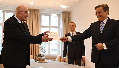 Bischof Dr. Felix Genn (links) übergibt die Ernennungsurkunde an Dr. Ralf Hammecke. Im Hintergrund Generalvikar Dr. Klaus Winterkamp.