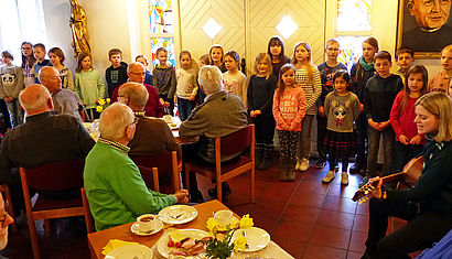 Ein Kinderchor singt Lieder vor Senioren. 