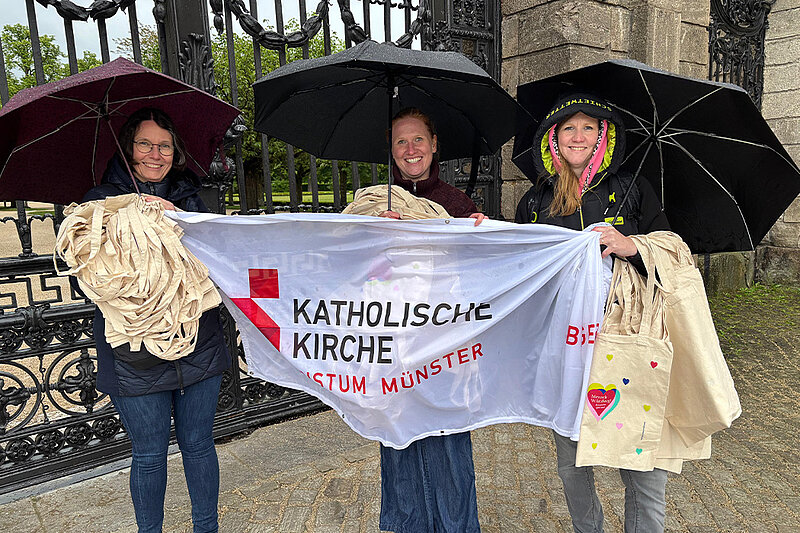 Wartende im Regen mit Stoffbeuteln und Regenschirm 