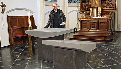 Pfarrer Arndt Thielen hält an dem neuen Altar die Steinplatte, mit der ein Hohlraum verschlossen werden kann, nachdem Reliquien in den Altar eingefügt worden sind. 