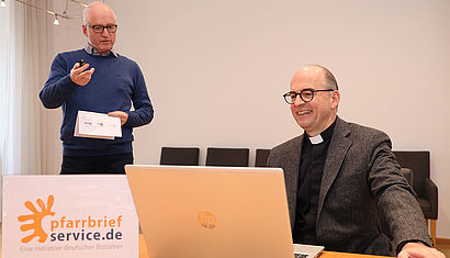 Johannes Simon (links), der Leiter von Pfarrbriefservice.de, zeigt Bischof Franz Jung (Würzburg) den neugestalteten Webauftritt