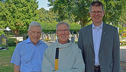 Auf dem Materborner Friedhof stehen (von links) Stephan Rintelen, Willi Quartier und Propst Johannes Mecking. Quartier trägt sein liturgisches Gewand, es ist hell und hat auf der rechten Seite einen breiten Streifen, oben schwarz und unten gelb.