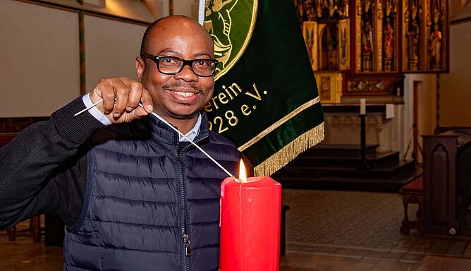 Ein Mann in einer Kirche zündet eine Kerze an.